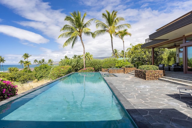 outdoor pool with a patio, a water view, and a ceiling fan