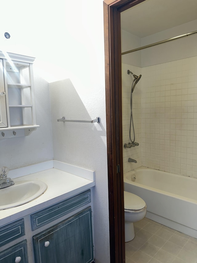 full bathroom featuring tiled shower / bath, tile patterned floors, vanity, and toilet