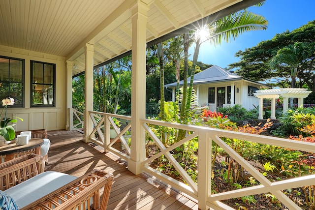 wooden terrace featuring covered porch and a pergola