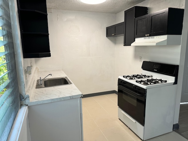 kitchen with white range with gas stovetop, light tile patterned floors, a textured ceiling, and sink