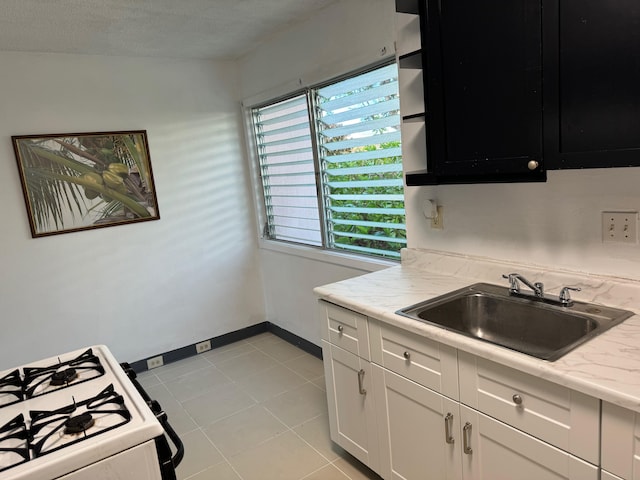 kitchen with white cabinets, sink, light stone countertops, light tile patterned floors, and white range with gas cooktop