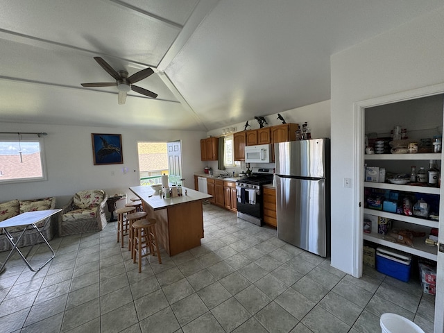 kitchen featuring a kitchen breakfast bar, a wealth of natural light, a kitchen island, and stainless steel appliances