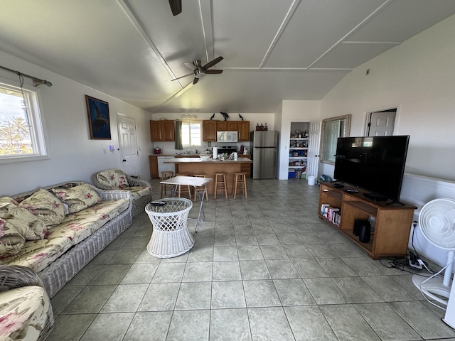 living room with ceiling fan, light tile patterned floors, a healthy amount of sunlight, and vaulted ceiling