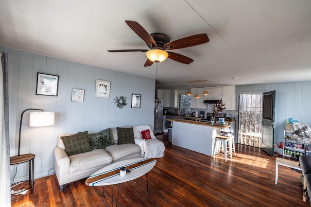 living room with ceiling fan and dark wood-type flooring