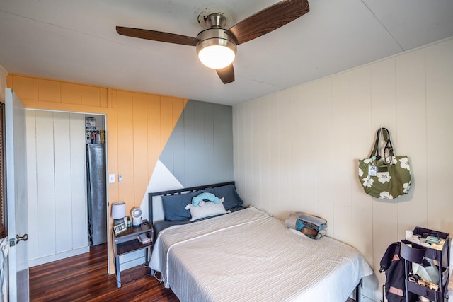 bedroom featuring ceiling fan, wood walls, and dark hardwood / wood-style floors