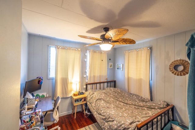 bedroom with ceiling fan, wood walls, and dark hardwood / wood-style floors