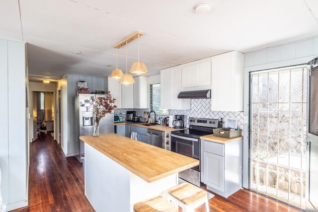 kitchen with wood counters, plenty of natural light, stainless steel appliances, and hanging light fixtures