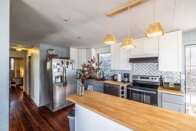 kitchen with butcher block countertops, plenty of natural light, stainless steel appliances, and hanging light fixtures