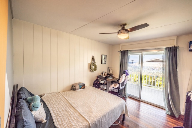 bedroom featuring access to exterior, ceiling fan, hardwood / wood-style floors, and wooden walls