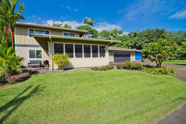 view of front facade featuring a sunroom, a garage, and a front lawn