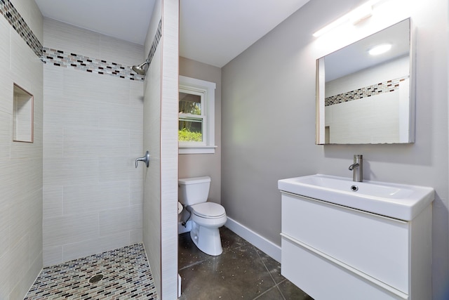 bathroom with tiled shower, vanity, and toilet