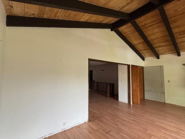 empty room featuring beam ceiling, wood ceiling, wood-type flooring, and high vaulted ceiling