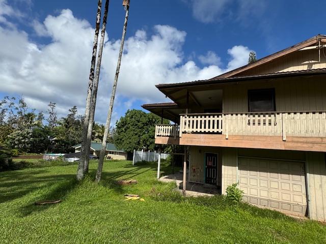 back of property with a lawn, a garage, and a wooden deck