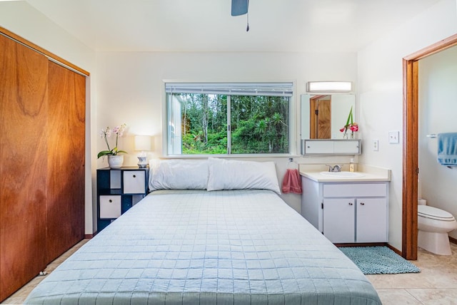 tiled bedroom with ceiling fan, sink, connected bathroom, and a closet