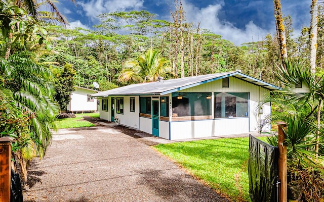 single story home featuring a sunroom and a front lawn