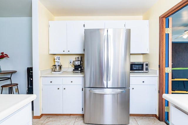 kitchen with white cabinets, stainless steel appliances, ceiling fan, and light tile patterned flooring