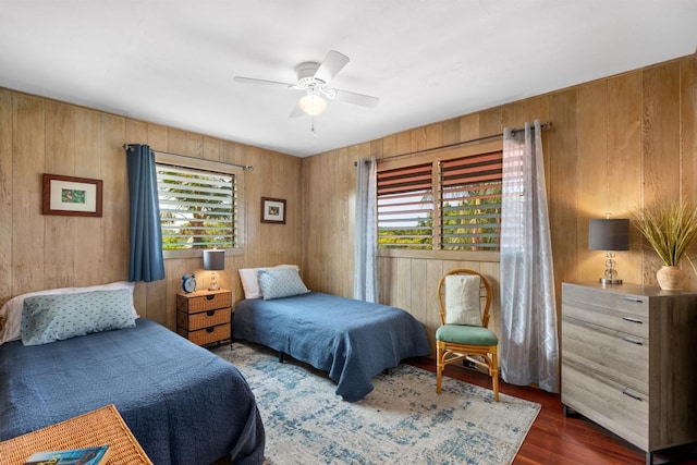 bedroom featuring dark wood-style floors, multiple windows, and wood walls