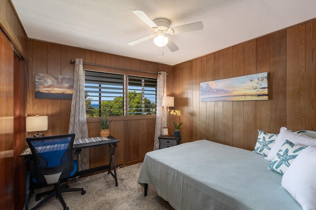 bedroom featuring carpet floors, ceiling fan, and wooden walls