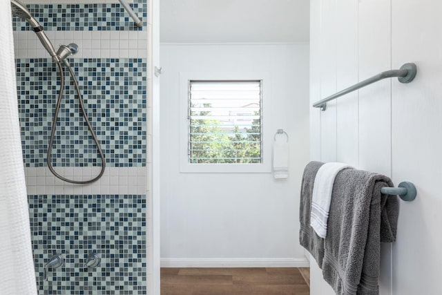 bathroom with a stall shower, baseboards, and wood finished floors