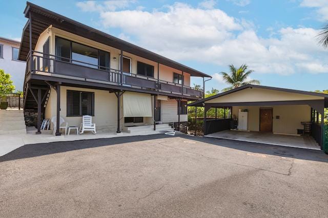 view of front of property featuring driveway and a balcony