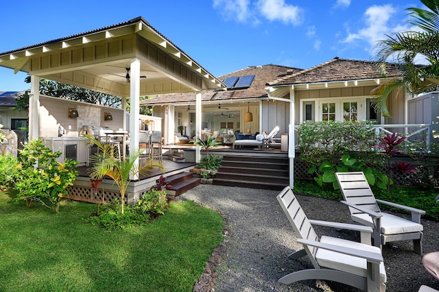 back of house featuring ceiling fan, a deck, and solar panels