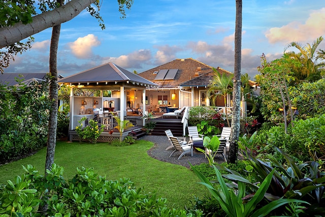 back house at dusk with outdoor lounge area and a yard