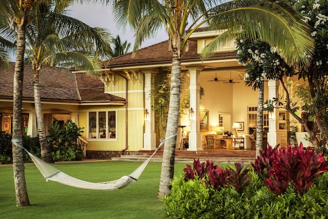 rear view of property featuring a lawn and ceiling fan