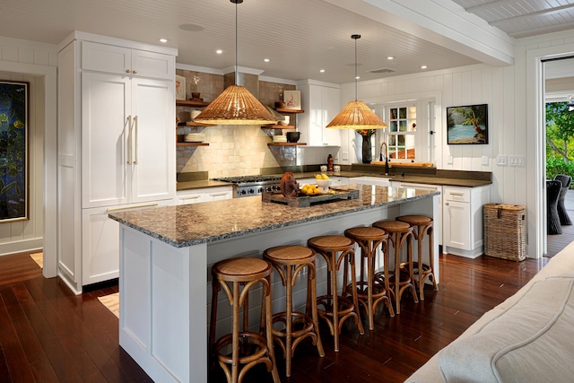 kitchen featuring white cabinets, decorative light fixtures, a kitchen island, and built in fridge