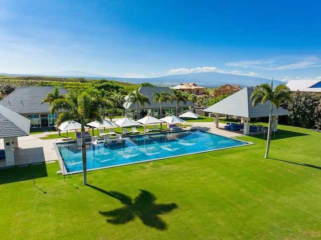 view of swimming pool with a mountain view, a patio area, and a yard