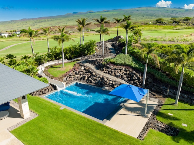 view of swimming pool featuring a mountain view, a yard, a patio, and a water slide