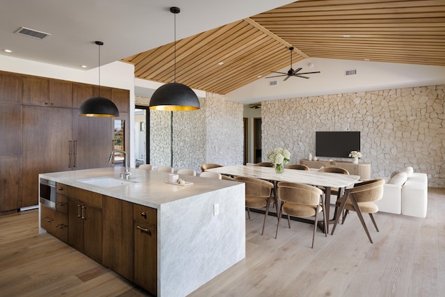 kitchen with sink, light hardwood / wood-style flooring, pendant lighting, a kitchen island with sink, and wood ceiling