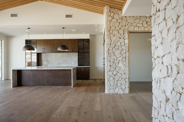 kitchen featuring dark brown cabinetry, high vaulted ceiling, backsplash, pendant lighting, and hardwood / wood-style flooring