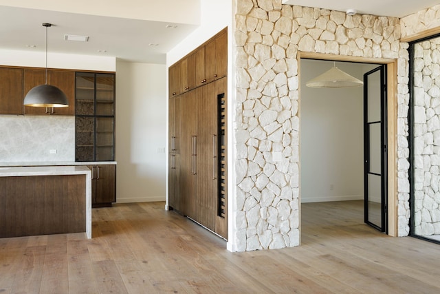 interior space featuring decorative backsplash, light hardwood / wood-style flooring, and decorative light fixtures