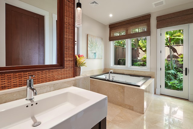 bathroom with tiled tub, tile patterned flooring, and vanity