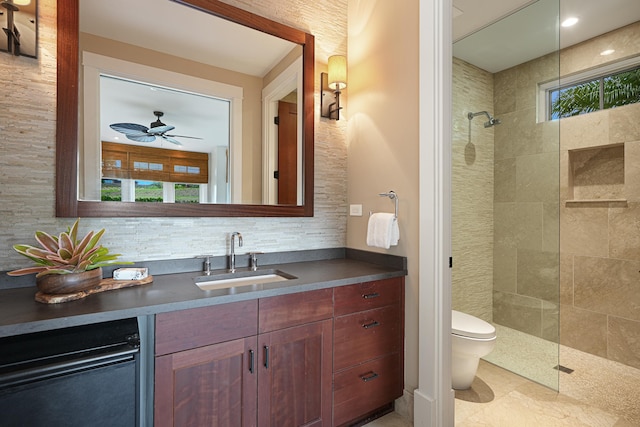 bathroom with a tile shower, vanity, toilet, and plenty of natural light