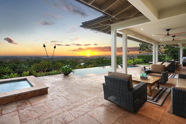 pool at dusk featuring an in ground hot tub, a patio, an outdoor hangout area, and ceiling fan