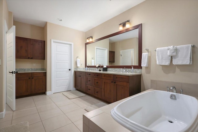 bathroom featuring tile patterned flooring, vanity, and tiled bath