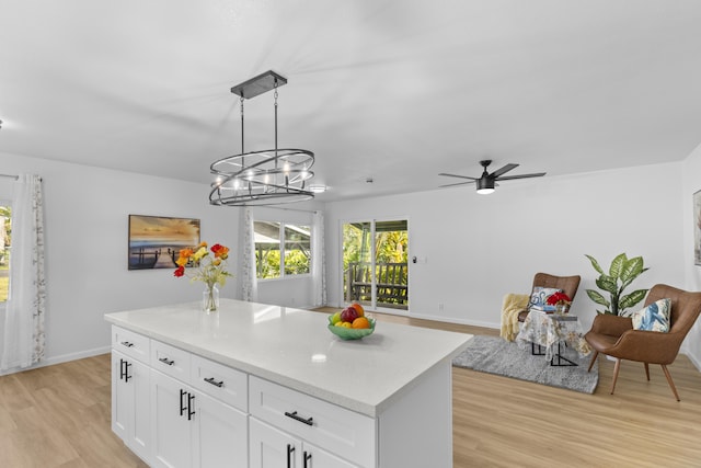 kitchen featuring light wood-type flooring, ceiling fan with notable chandelier, a kitchen island, white cabinetry, and hanging light fixtures