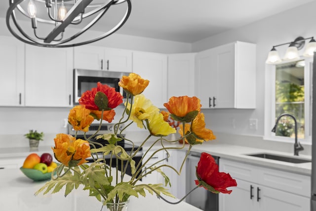 room details featuring sink, white cabinets, and an inviting chandelier