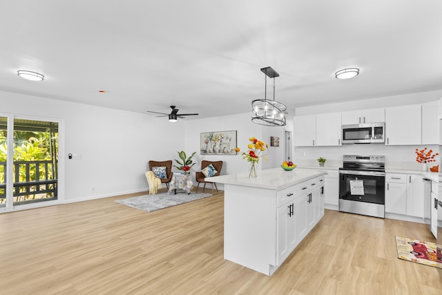 kitchen with white cabinetry, a center island, stainless steel appliances, pendant lighting, and light wood-type flooring