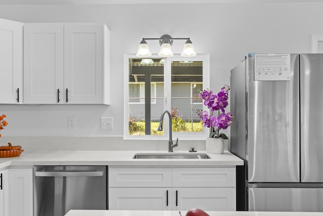 kitchen with stainless steel appliances, white cabinetry, and sink