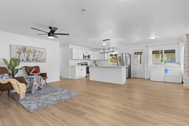 living room featuring ceiling fan with notable chandelier, light hardwood / wood-style floors, and washing machine and dryer