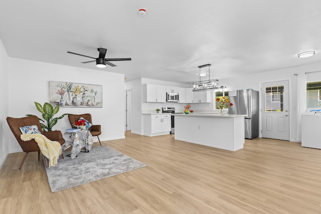 interior space with stainless steel appliances, a kitchen island, decorative light fixtures, washer / dryer, and white cabinetry