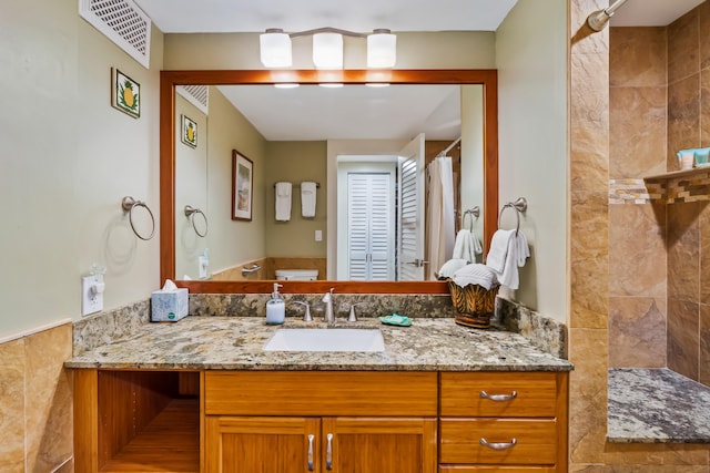 bathroom with a shower, vanity, and tile walls