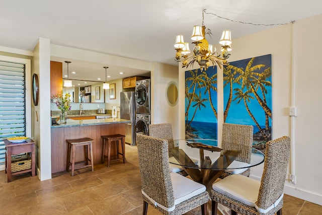 dining space featuring an inviting chandelier, sink, and stacked washer and clothes dryer