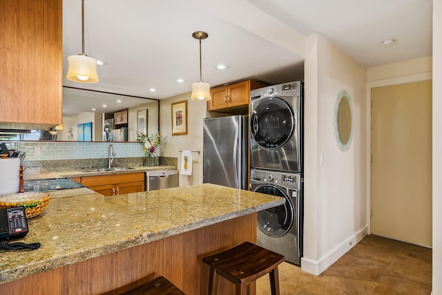 kitchen featuring kitchen peninsula, appliances with stainless steel finishes, stacked washing maching and dryer, and sink