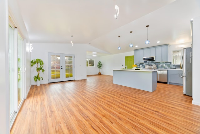 kitchen with stainless steel appliances, decorative light fixtures, light hardwood / wood-style flooring, a center island, and lofted ceiling