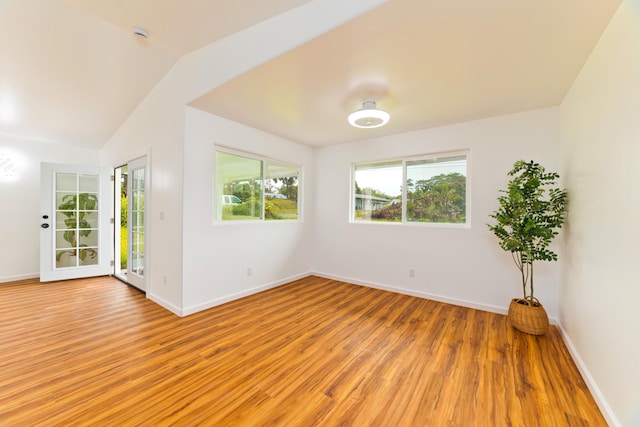 unfurnished room with light hardwood / wood-style floors and lofted ceiling