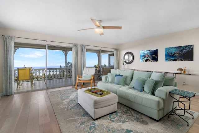 living room with hardwood / wood-style floors, a water view, and ceiling fan