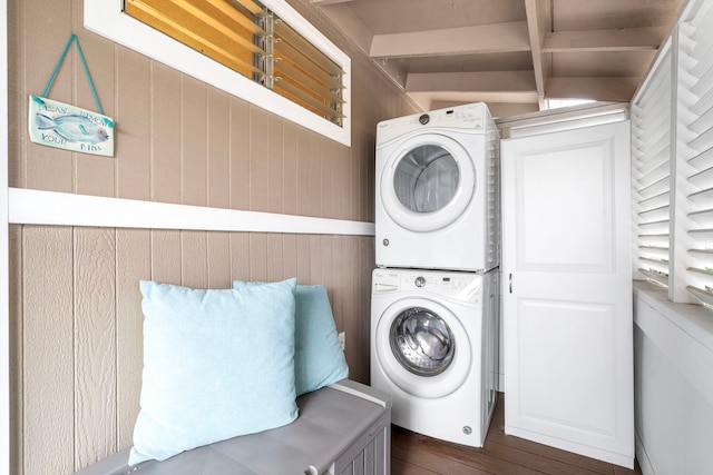 washroom featuring stacked washing maching and dryer and wooden walls